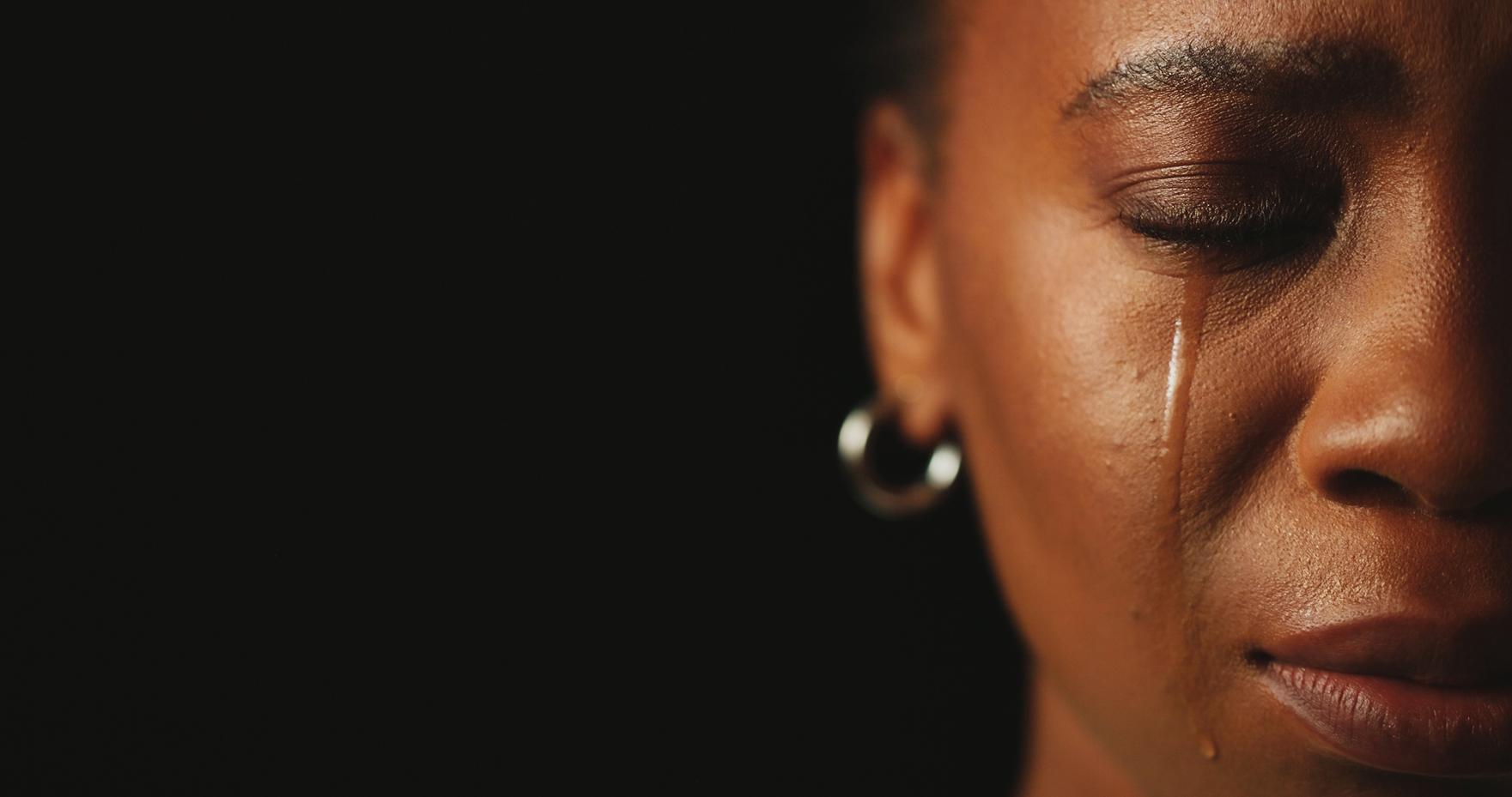 Close-up profile of a person with eyes closed and pearl earrings against a dark background.